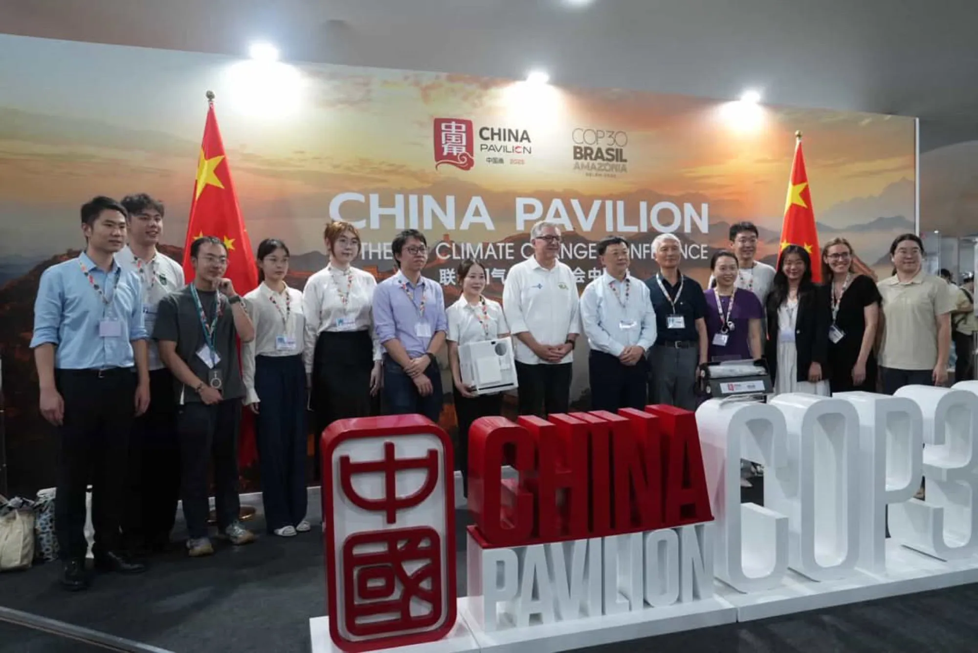 A group photograph in front of the China Pavilion display at COP30 in Belém.
