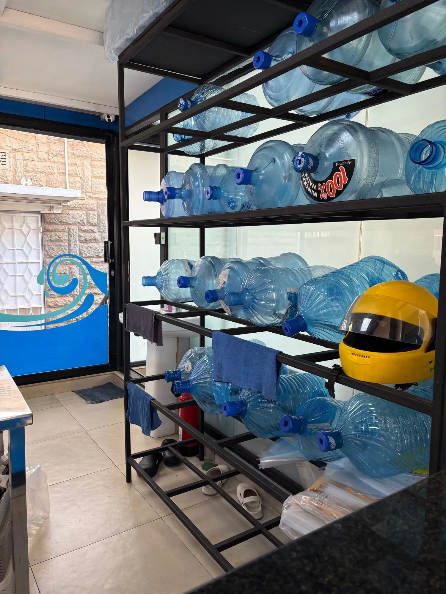Racks of large blue refill bottles inside a water shop.